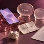 A phone beside rose glass speech bubbles and a handwritten note asking what to say